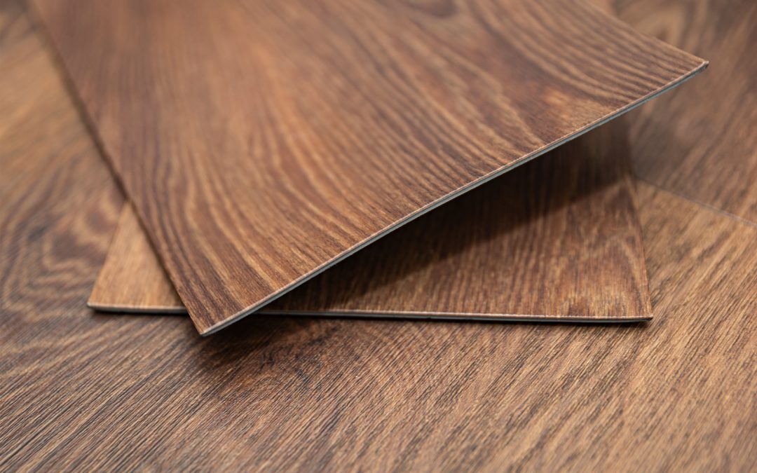 Two pieces of brown wood-patterned vinyl flooring planks overlap on a matching wood-pattern surface, offering an elegant flooring option for kitchen remodeling Maryland projects.