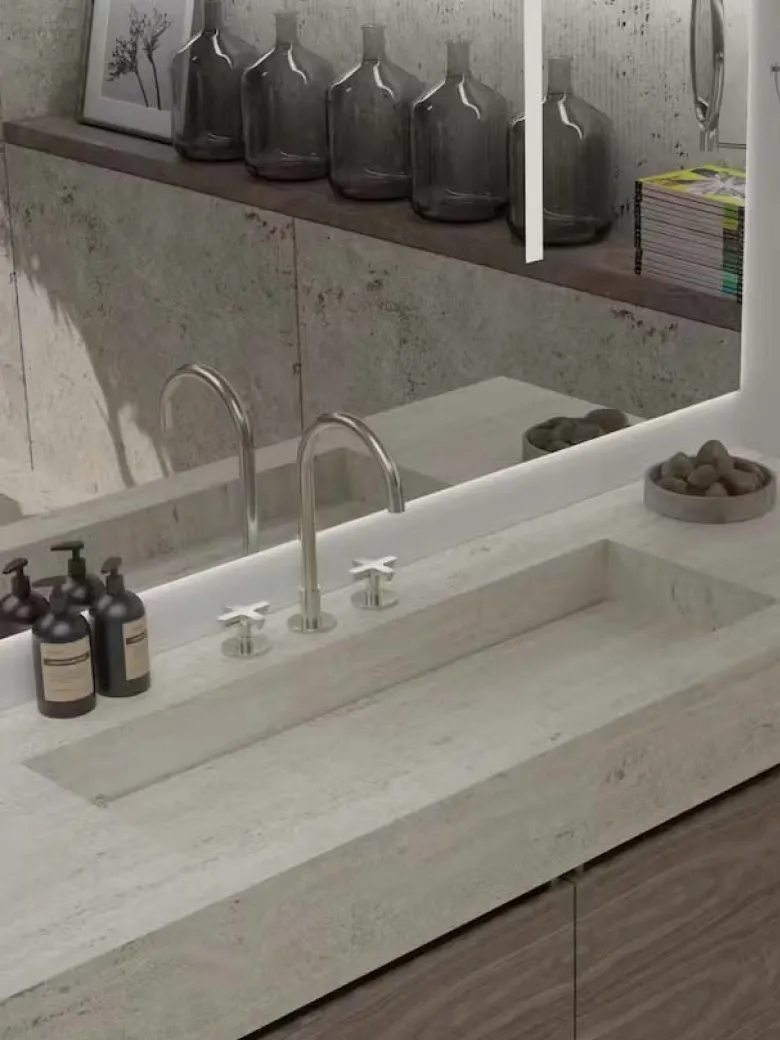 Modern bathroom sink with stone countertop, soap dispensers, and decorative jars reflected in a mirror.