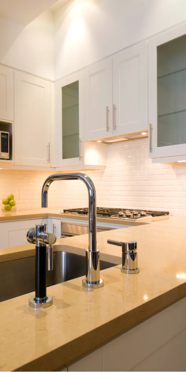 Bathroom Fixtures Installation: Modern kitchen with white cabinets, a stainless steel sink, chrome faucet, and beige countertop.