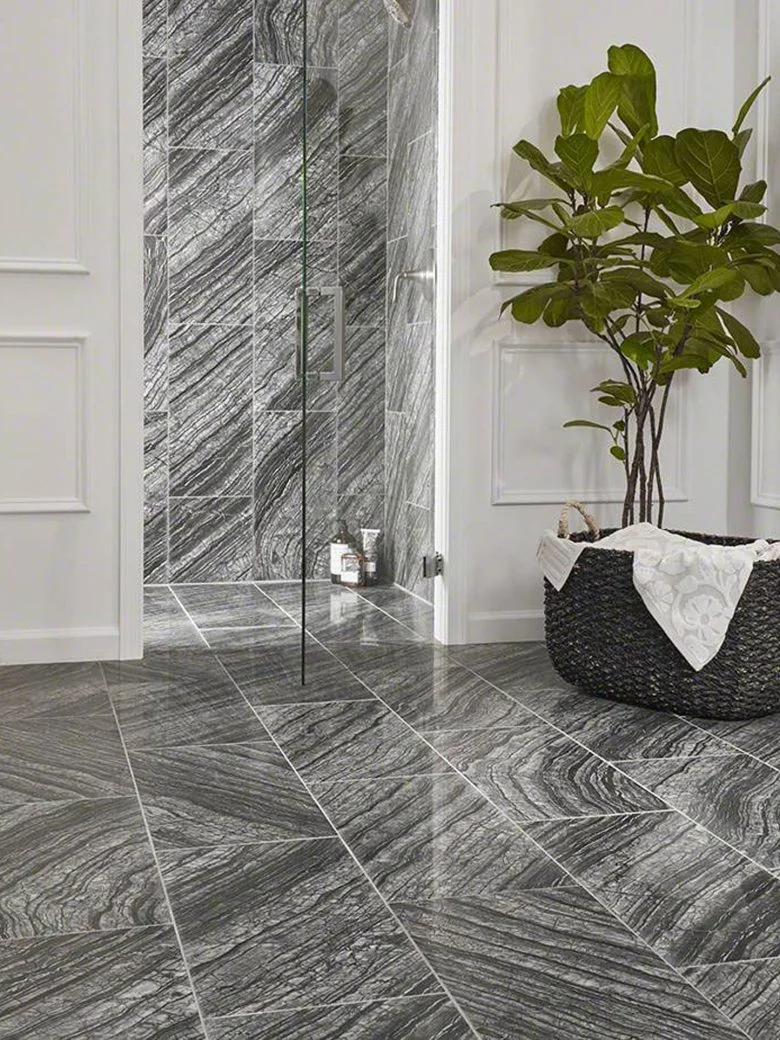 Remodeling Products: Bathroom with gray marble tile, glass shower door, potted plant, and a woven basket with a white towel.